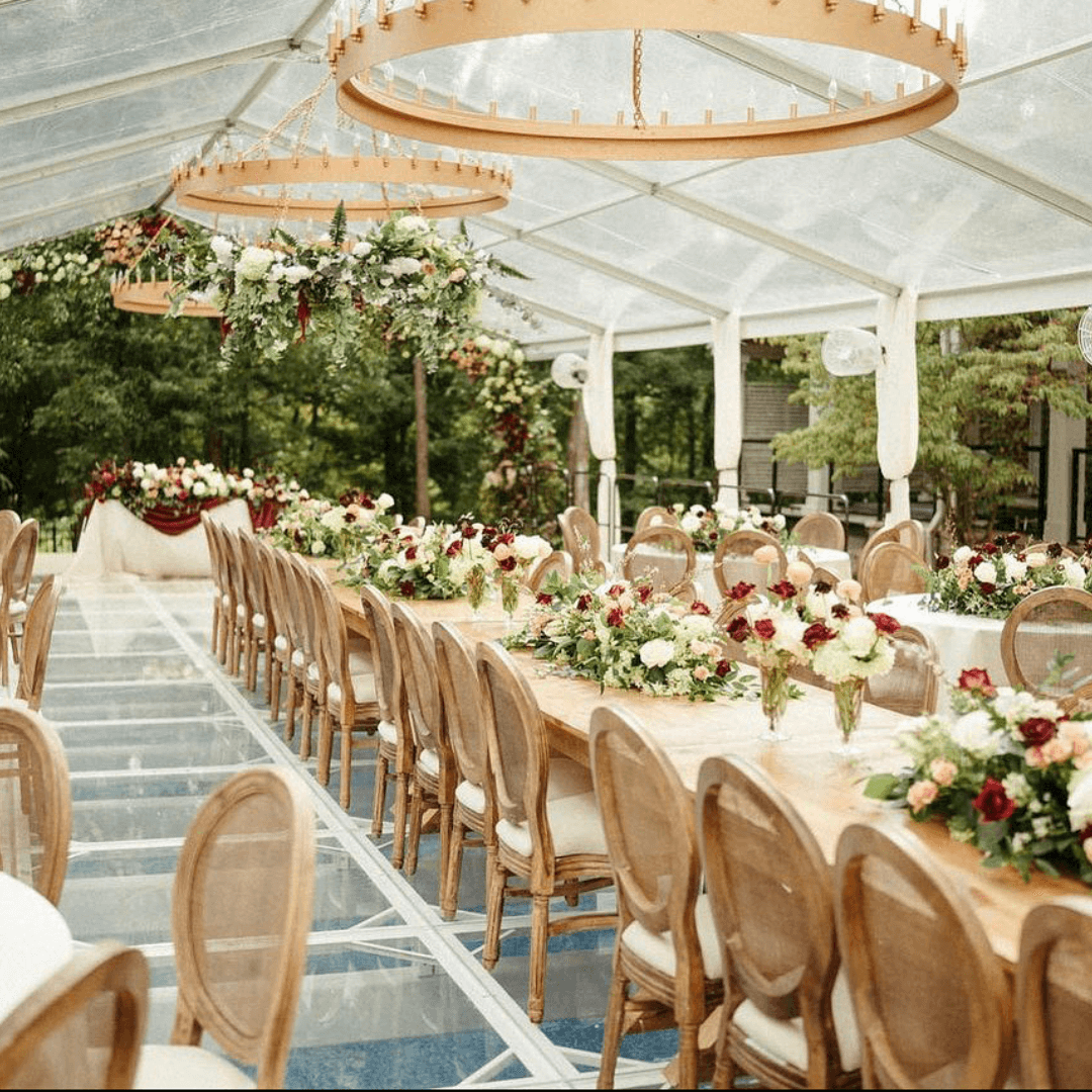 A reception venue with wooden tables and chairs, and white, pink, and red flowers