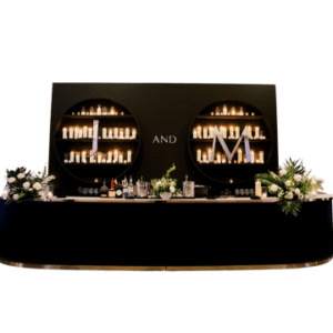 A black cocktail bar with candles and flowers and other decor arranged for a reception